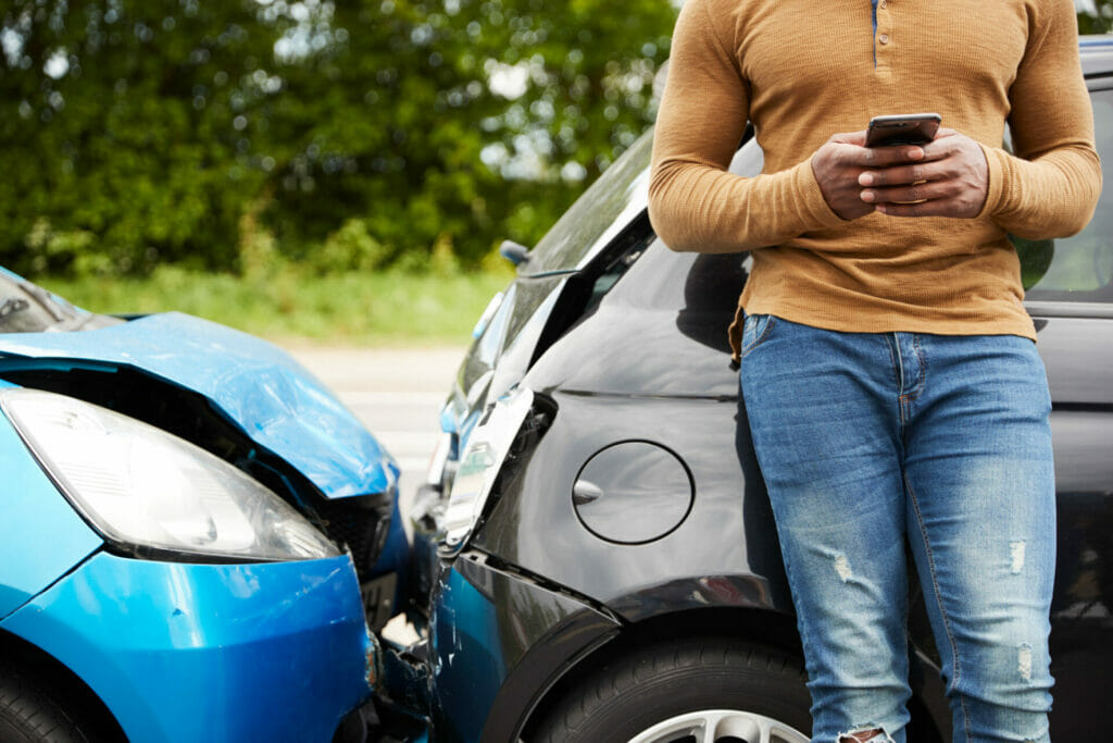 Man involved in an accident using his phone to see whose fault the accident is