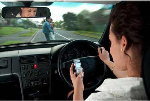 A woman driving a car while using her cell phone.