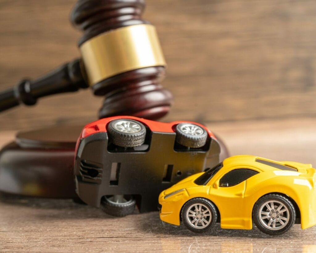 Rose Sanders Law Firm - Best Car Accident Lawyer; A toy car and a gavel on a wooden table.