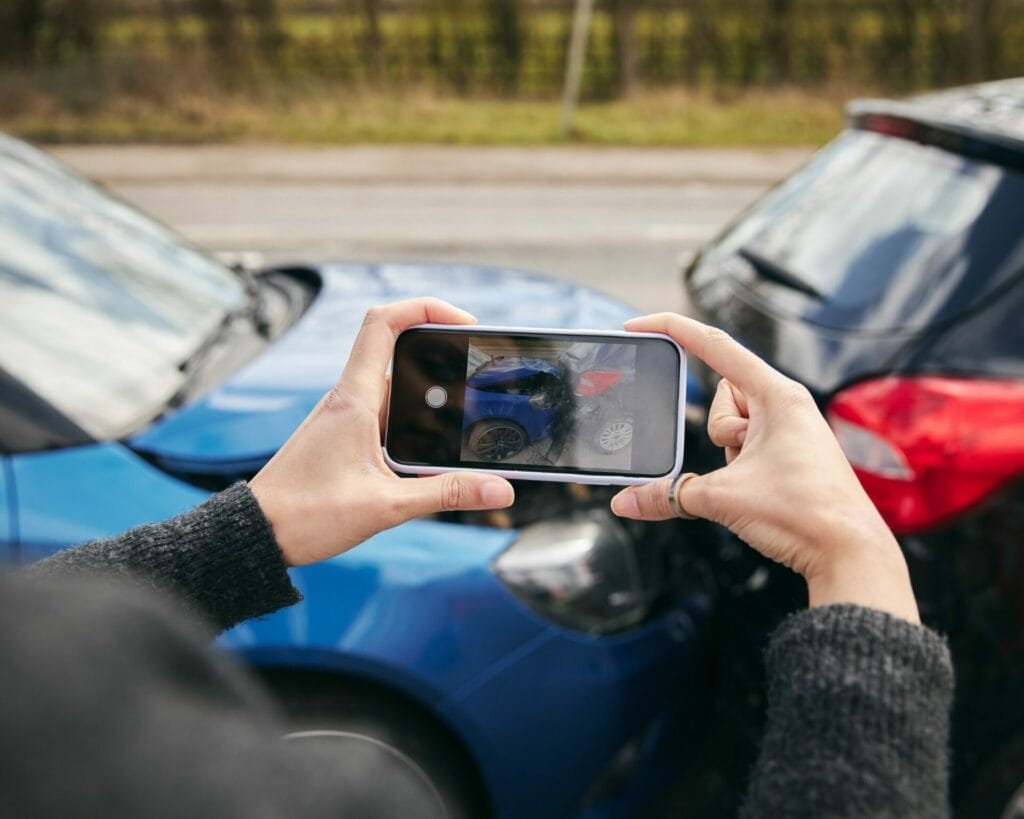 A person taking a picture of a damaged car.
