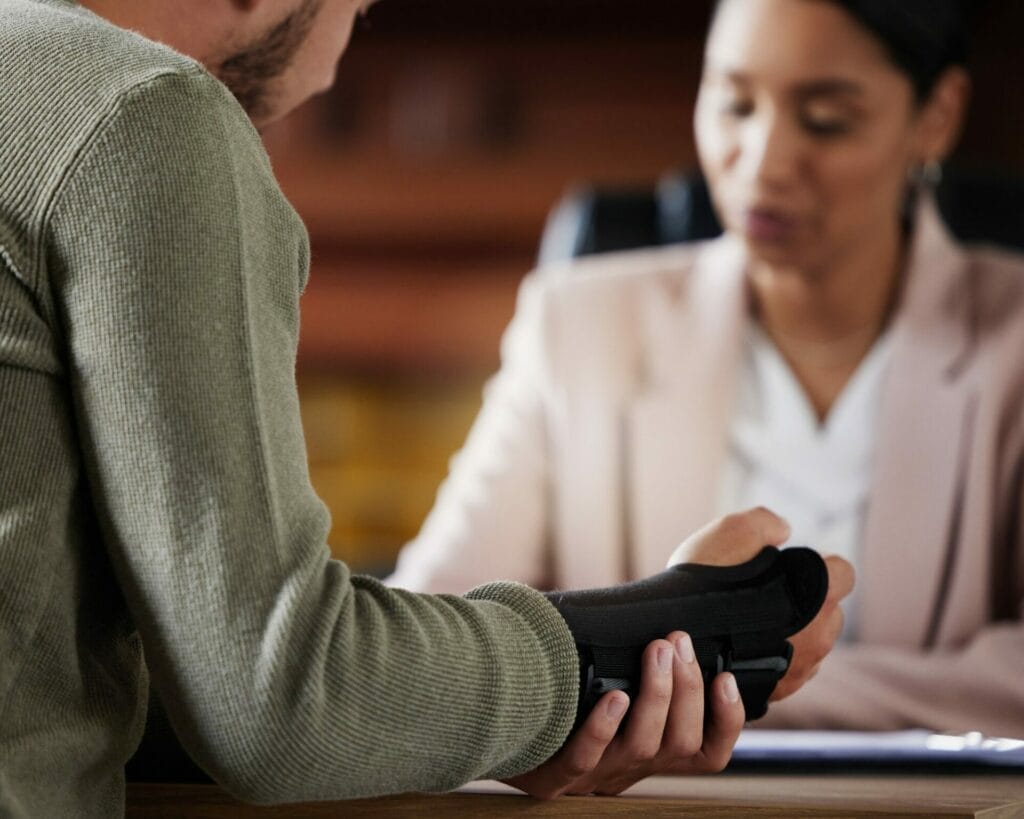 The Rose Sanders Law Firm - Car Accident Lawyer meeting; A man with a broken arm sitting at a desk.