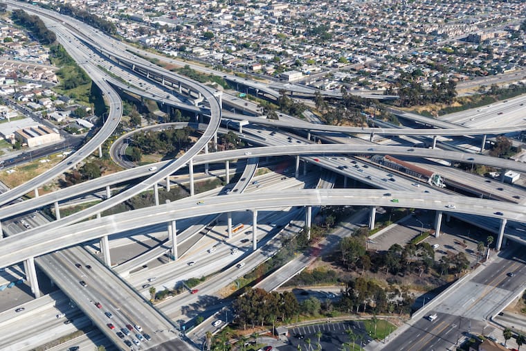 Aerial view of a large multi-level highway interchange with numerous overpasses and roads intersecting, surrounded by urban residential areas.